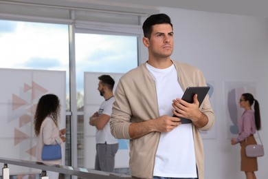 Photo of Thoughtful man with tablet at exhibition in art gallery