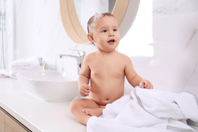 Cute little baby sitting on countertop in bathroom