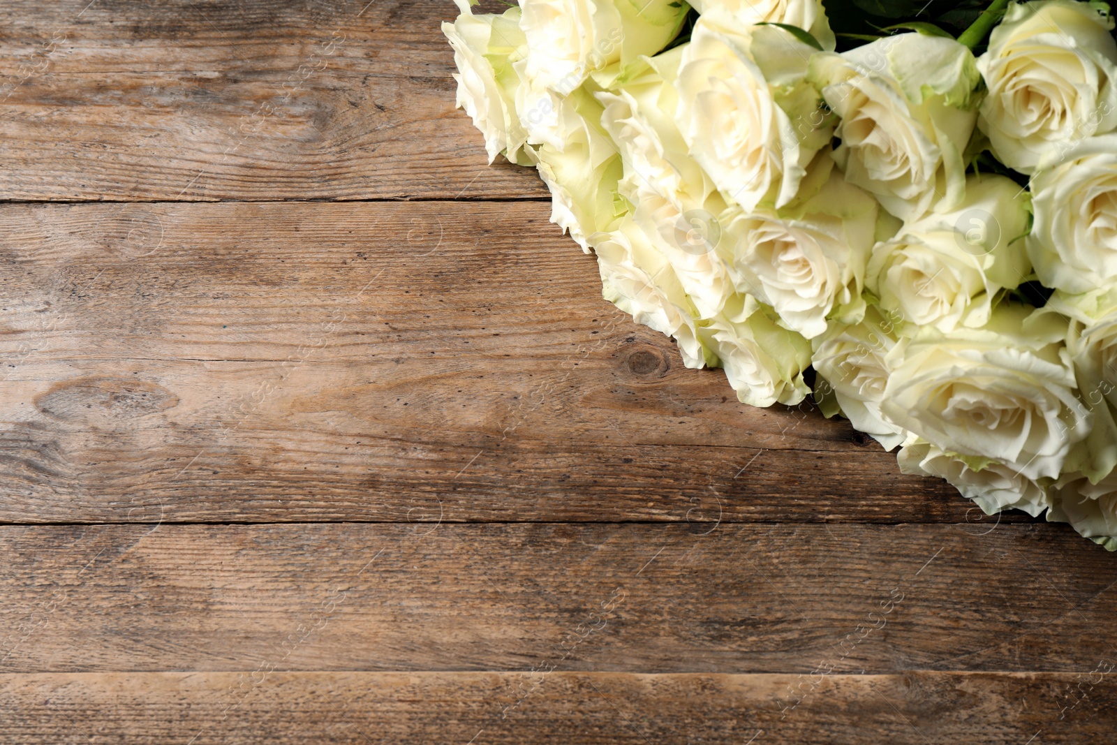 Photo of Luxury bouquet of fresh roses on wooden table. Space for text