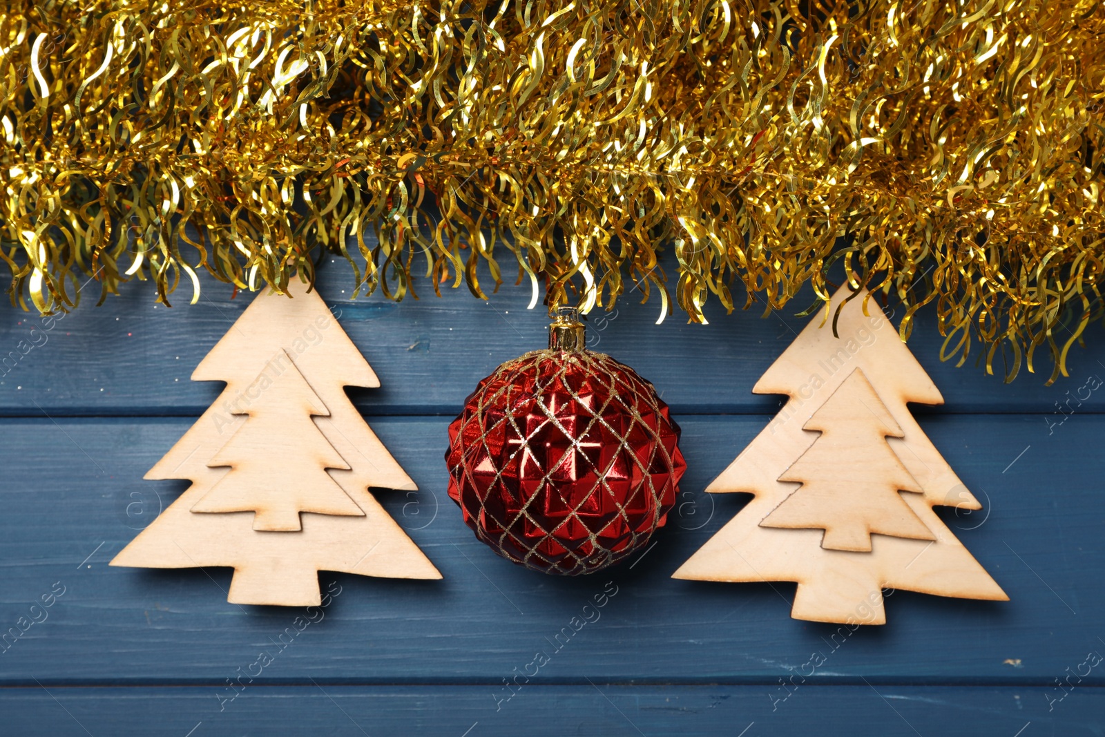 Photo of Bright tinsel and Christmas decor on blue wooden background, flat lay