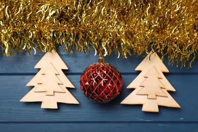 Bright tinsel and Christmas decor on blue wooden background, flat lay