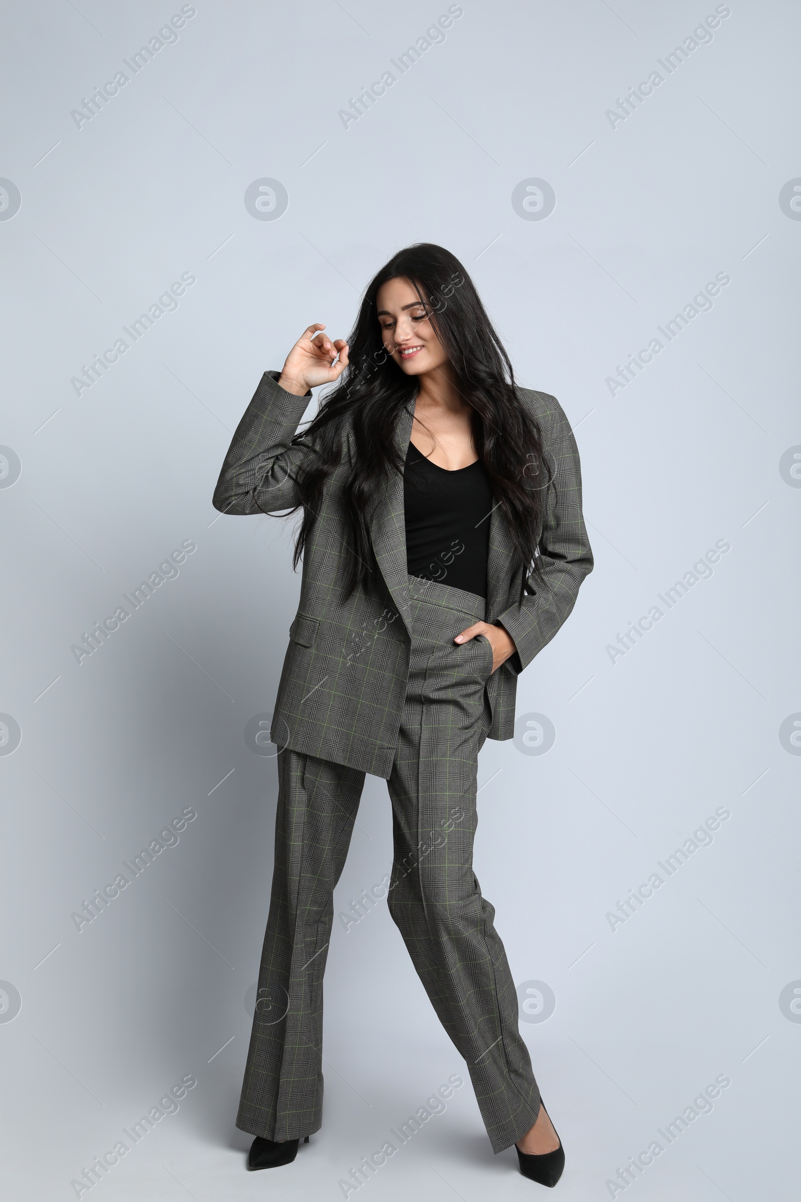 Photo of Full length portrait of beautiful woman in formal suit on light background. Business attire