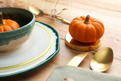 Photo of Autumn table setting with pumpkins on wooden background, closeup