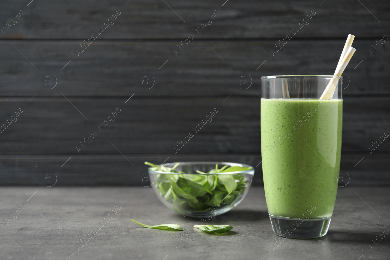 Photo of Glass of healthy green smoothie with fresh spinach on grey table. Space for text