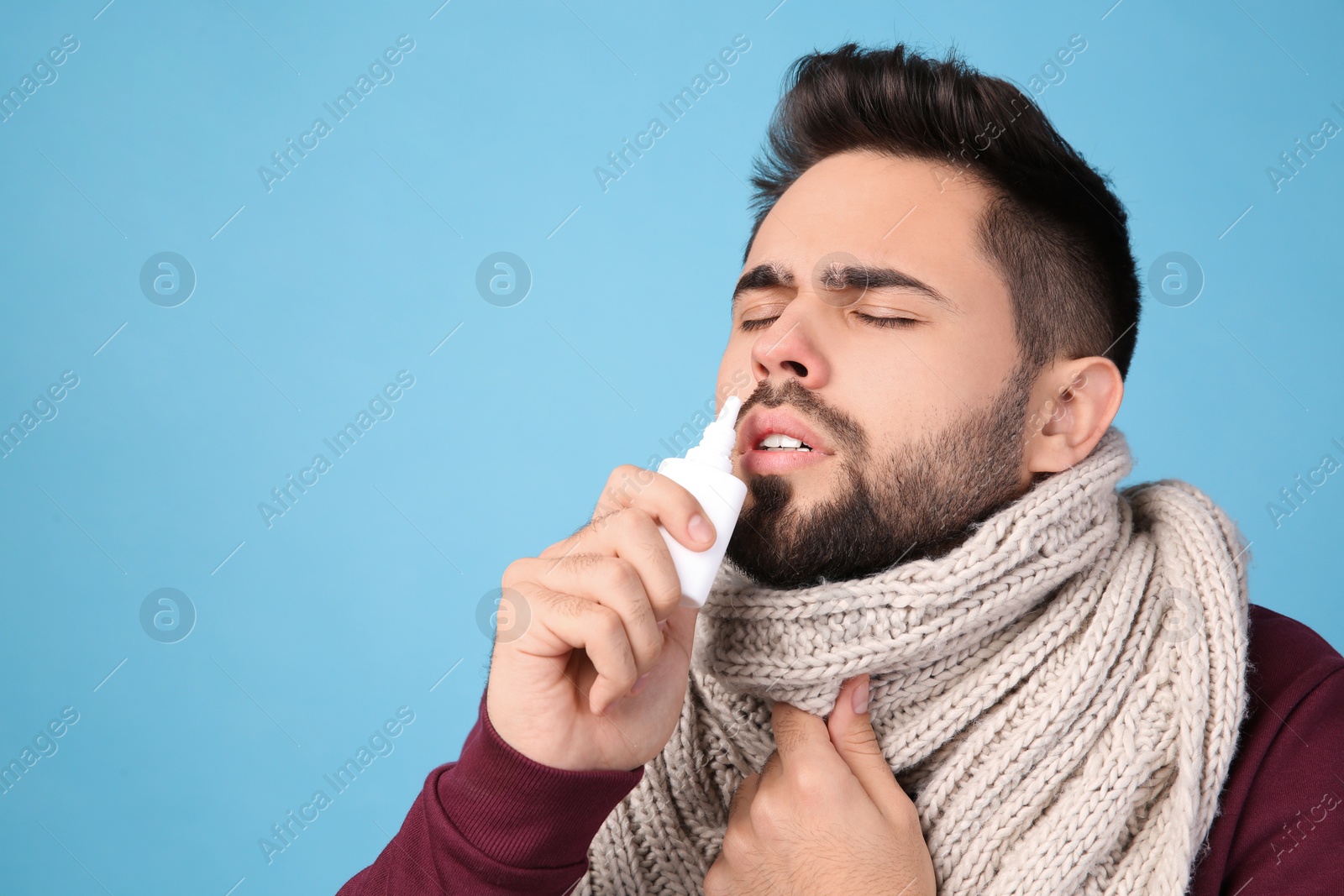 Photo of Man using nasal spray on light blue background, space for text