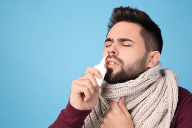 Photo of Man using nasal spray on light blue background, space for text