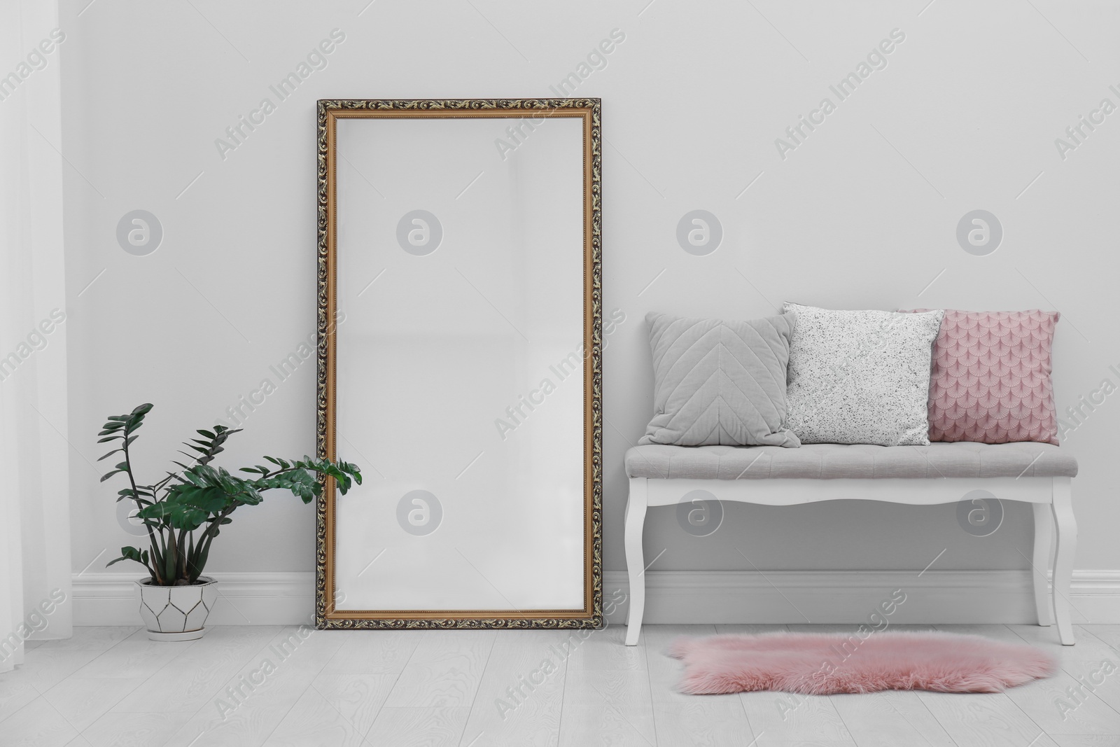 Photo of Modern large mirror and comfortable bench near light wall in room