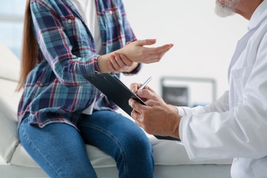 Orthopedist examining patient with injured hand in clinic, closeup