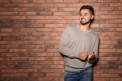 Image of Handsome man wearing warm sweater near brick wall. Space for text