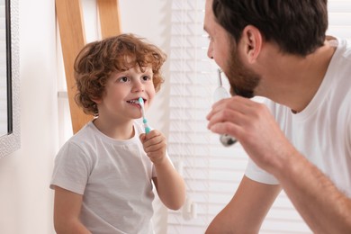 Photo of Father and his son brushing teeth together in bathroom