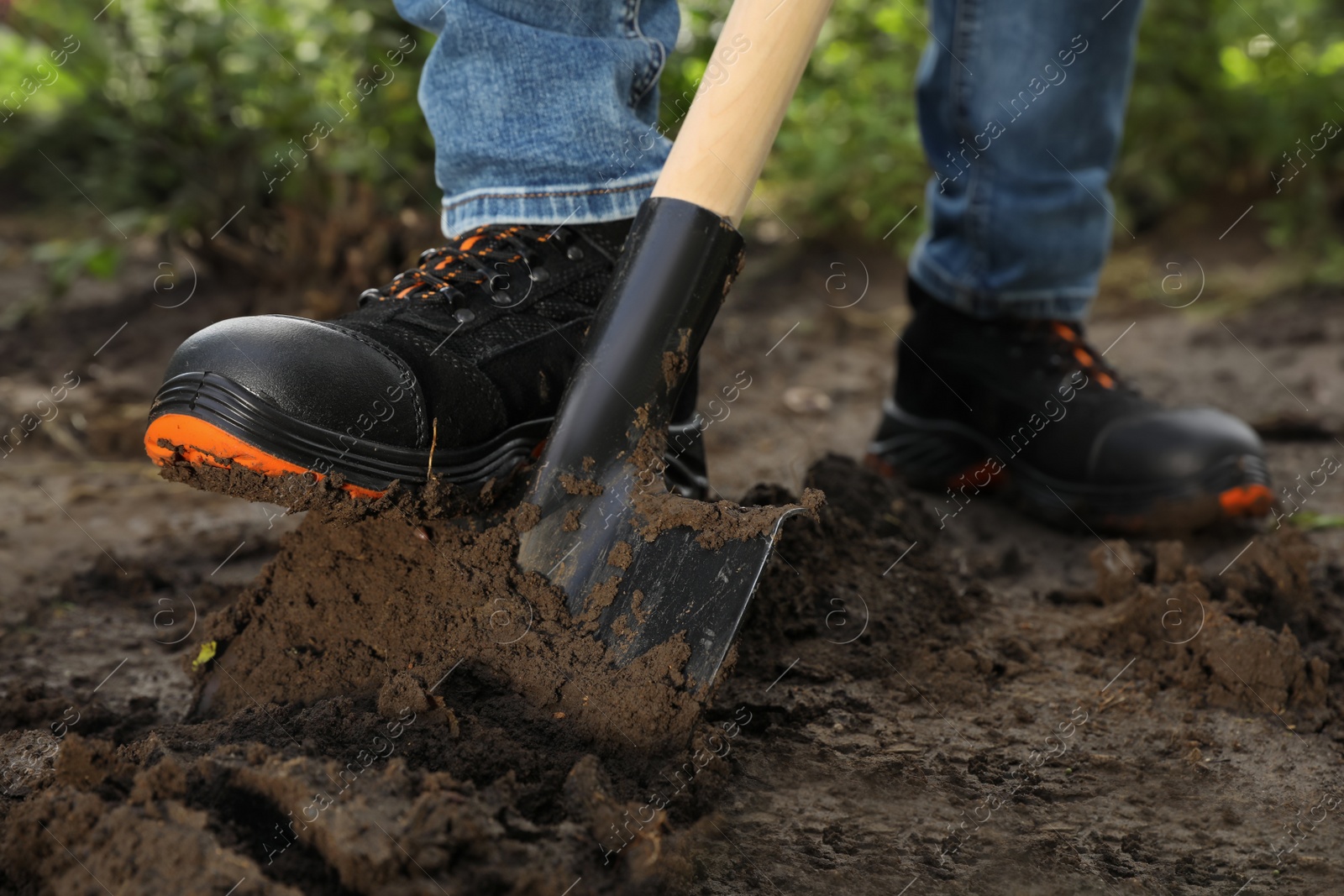 Photo of Worker digging soil with shovel outdoors, closeup