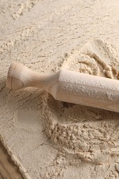 Photo of Flour and rolling pin on wooden table, above view