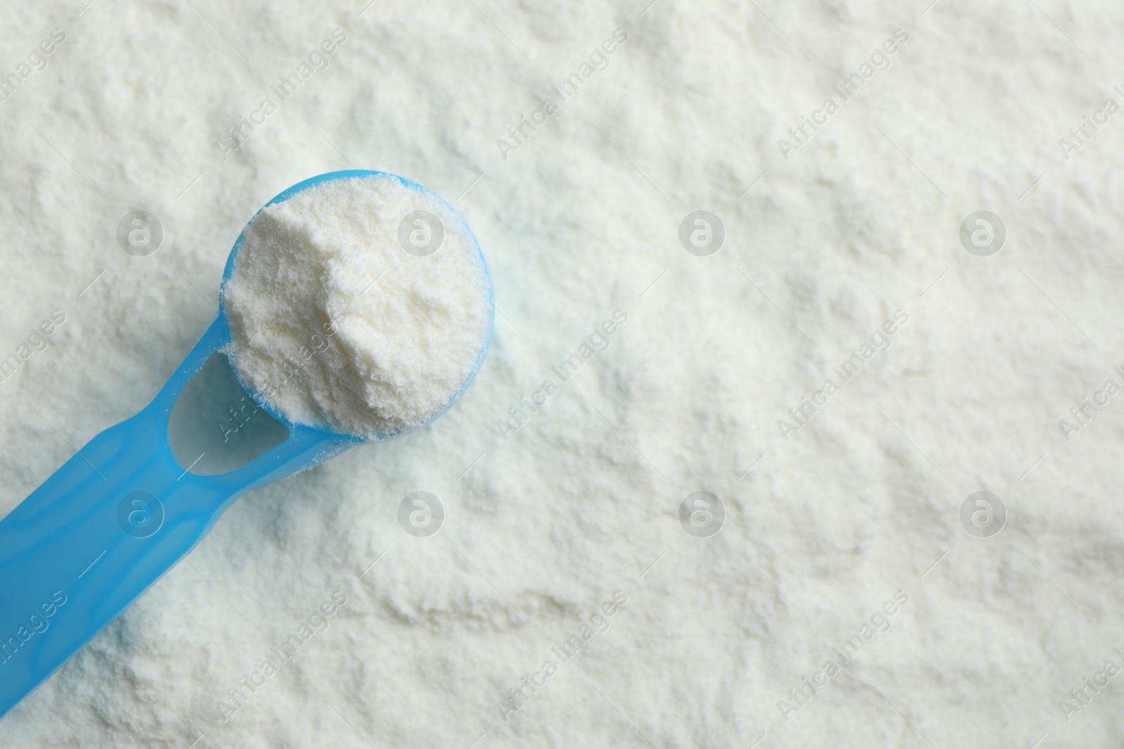 Photo of Top view of powdered infant formula and scoop, space for text. Baby milk