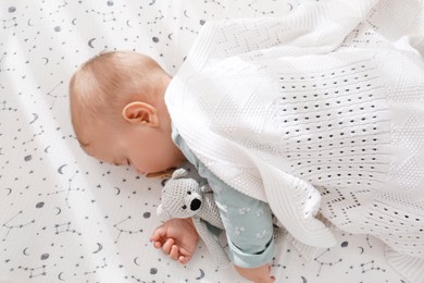 Photo of Adorable baby with toy sleeping in bed, above view