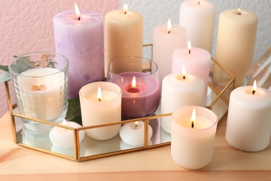 Set of burning candles on table against color background