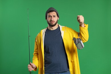 Photo of Confused fisherman with fishing rod and tin can on green background