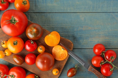 Photo of Flat lay composition of fresh ripe whole and cut tomatoes on blue wooden table