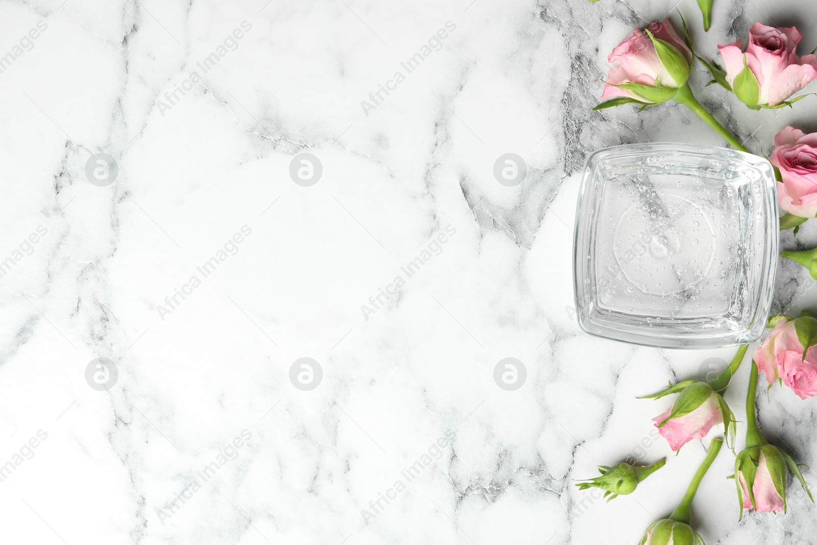 Photo of Flat lay composition with cosmetic gel and beautiful flowers on white marble table. Space for text