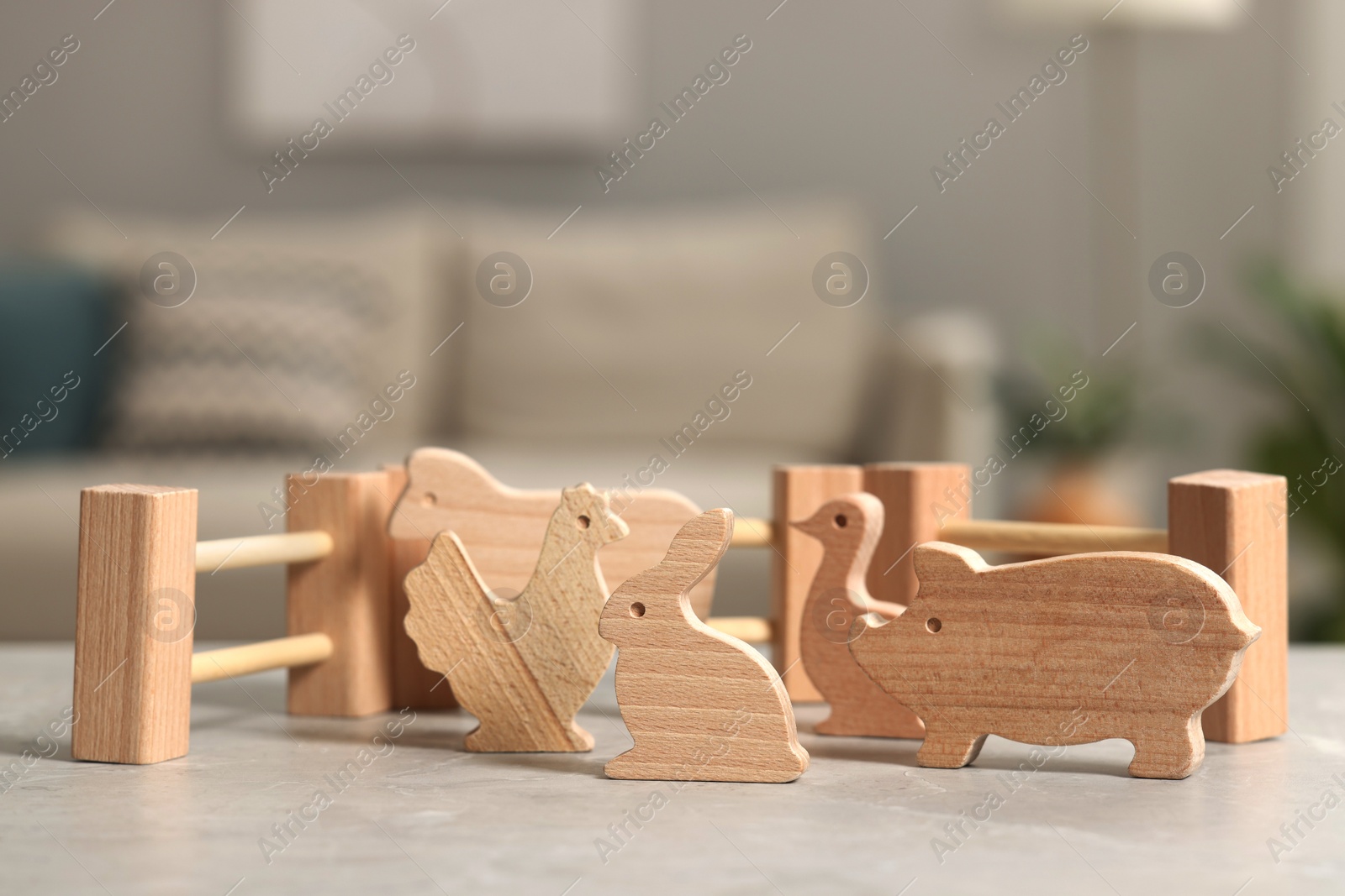 Photo of Wooden animals and fence on light grey table indoors, closeup. Children's toys