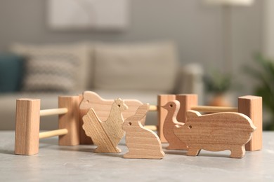 Wooden animals and fence on light grey table indoors, closeup. Children's toys