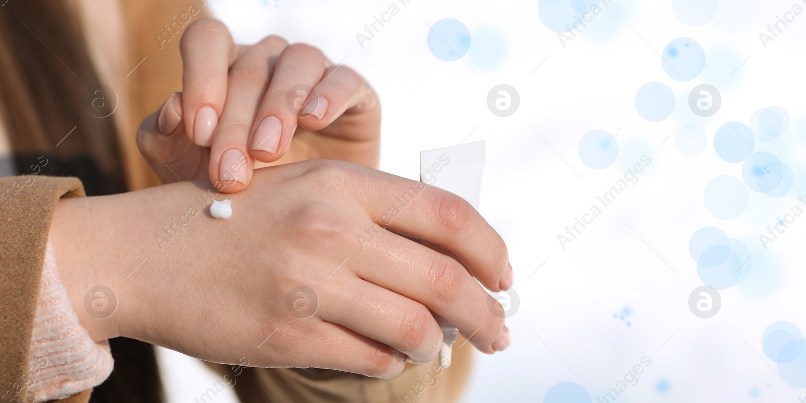 Image of Woman applying moisturizing cream on hands on white background, closeup. Banner design