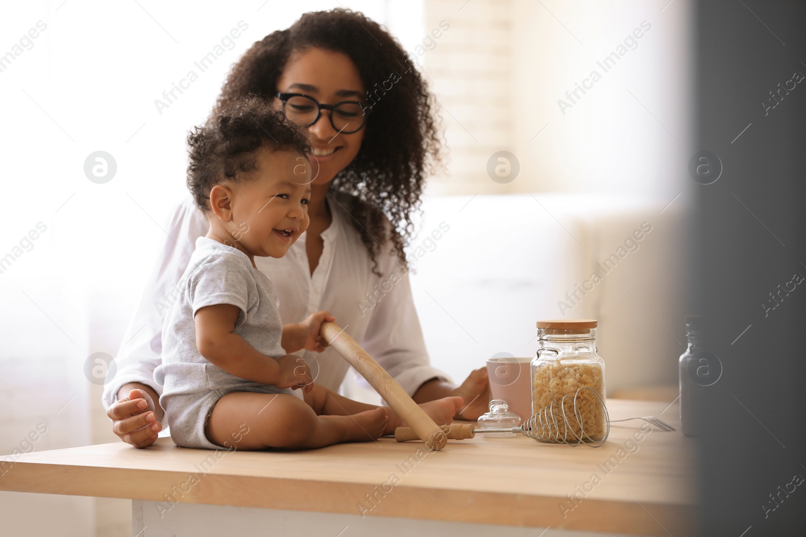 Photo of African-American woman with her baby in kitchen. Happiness of motherhood