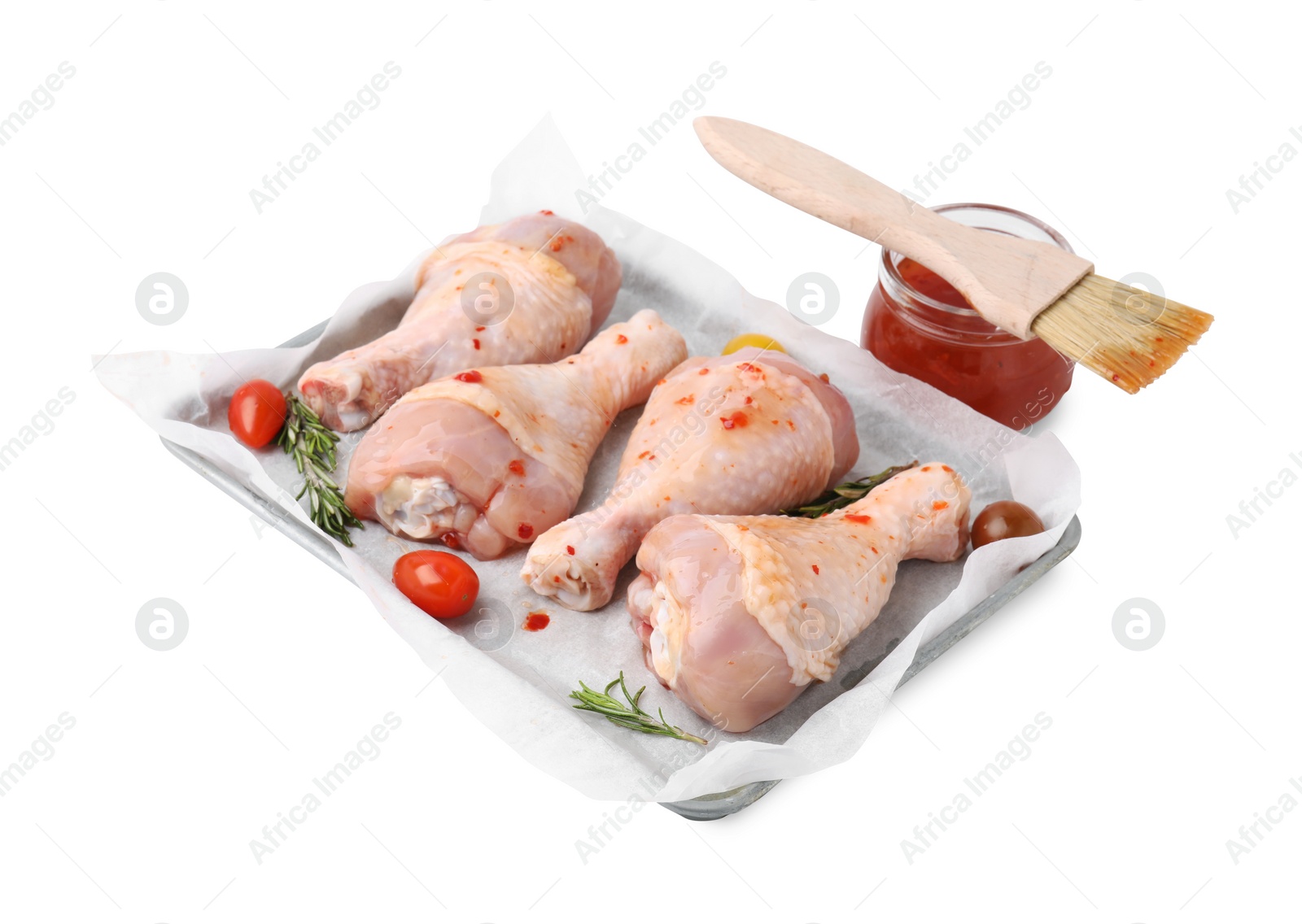 Photo of Marinade, brush, raw chicken drumsticks, rosemary and tomatoes isolated on white