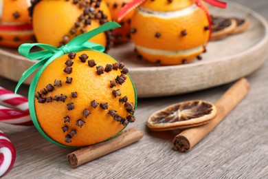 Photo of Pomander balls made of tangerines with cloves on wooden table, closeup