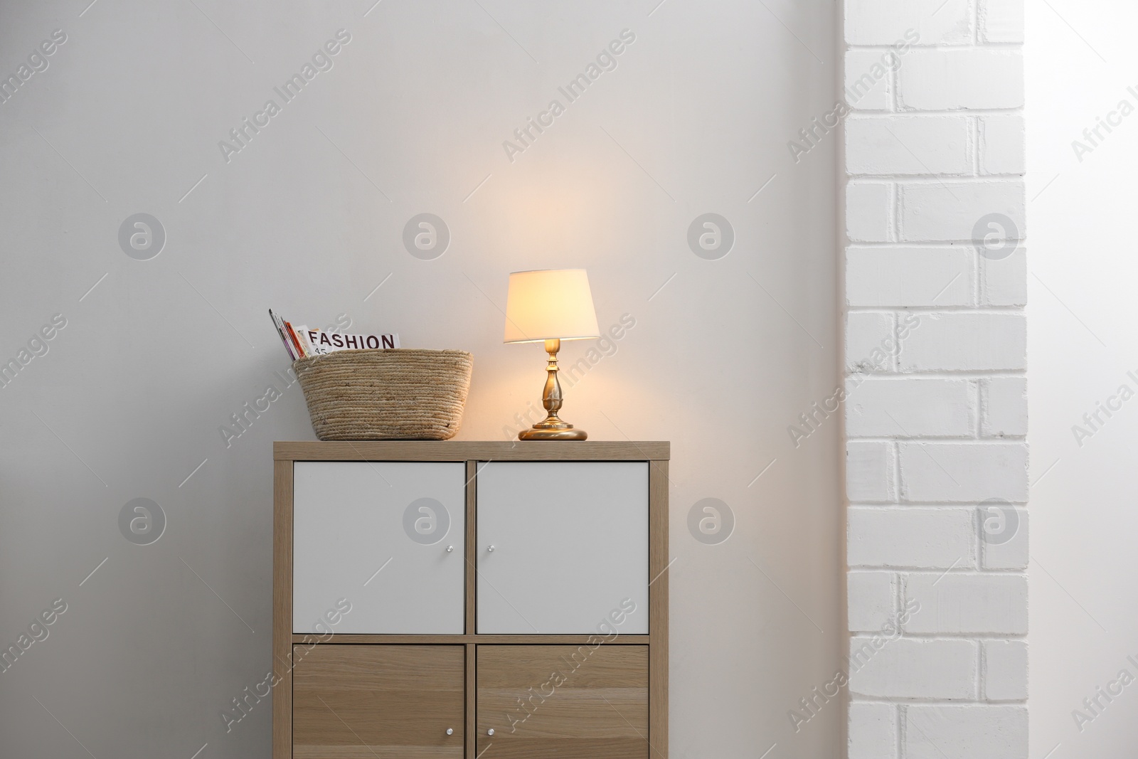 Photo of Stylish cabinet with lamp in living room