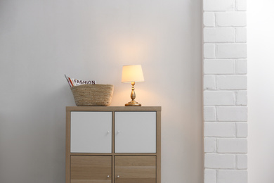 Photo of Stylish cabinet with lamp in living room