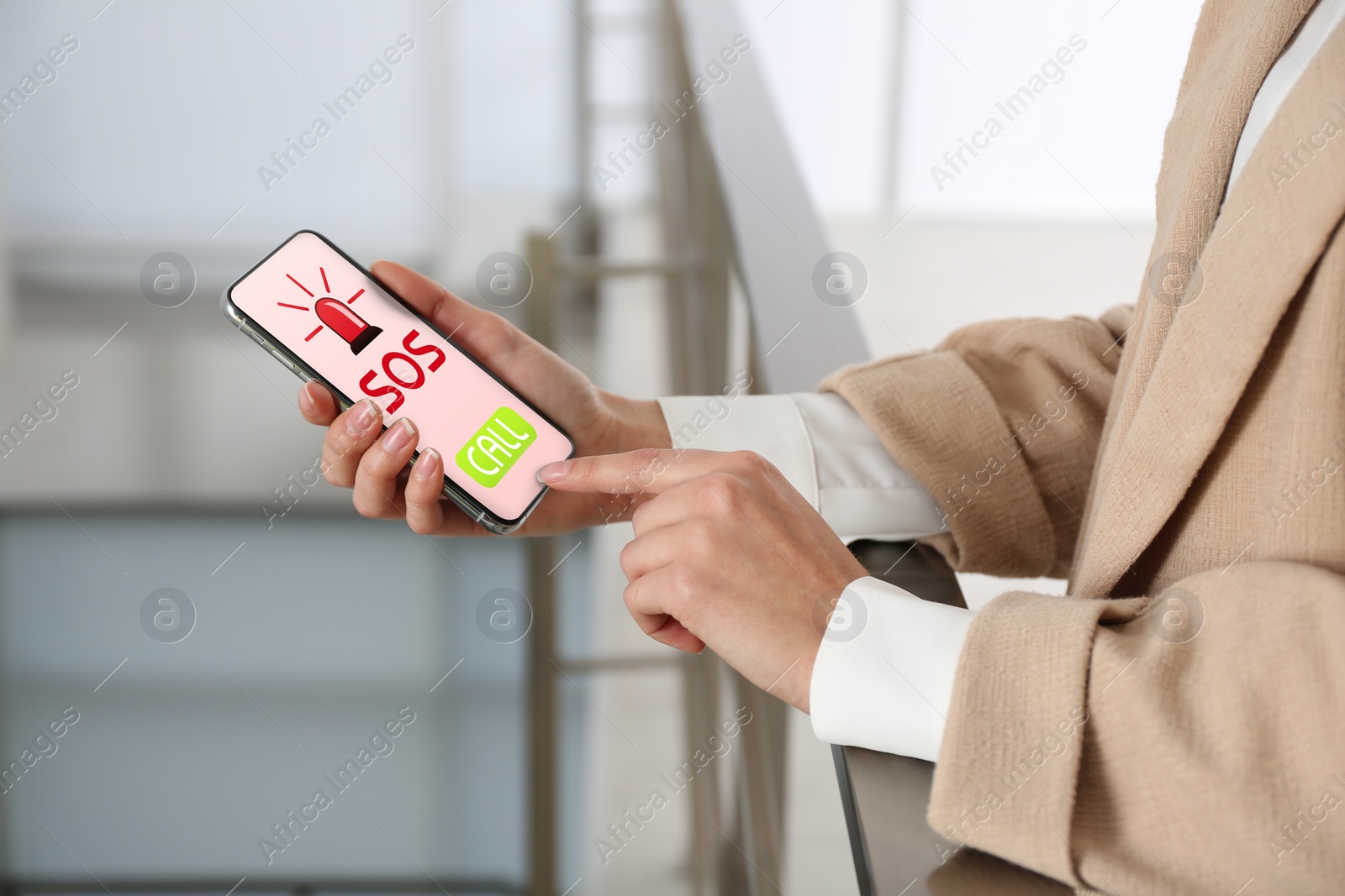 Image of Woman holding smartphone with emergency call SOS on screen indoors, closeup