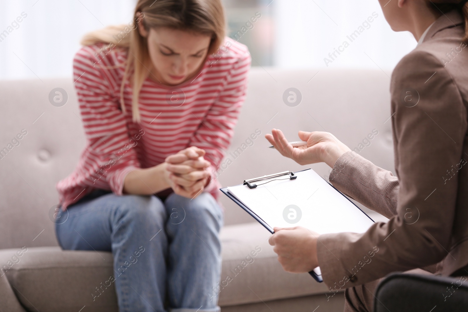 Photo of Psychotherapist working with young woman in light office