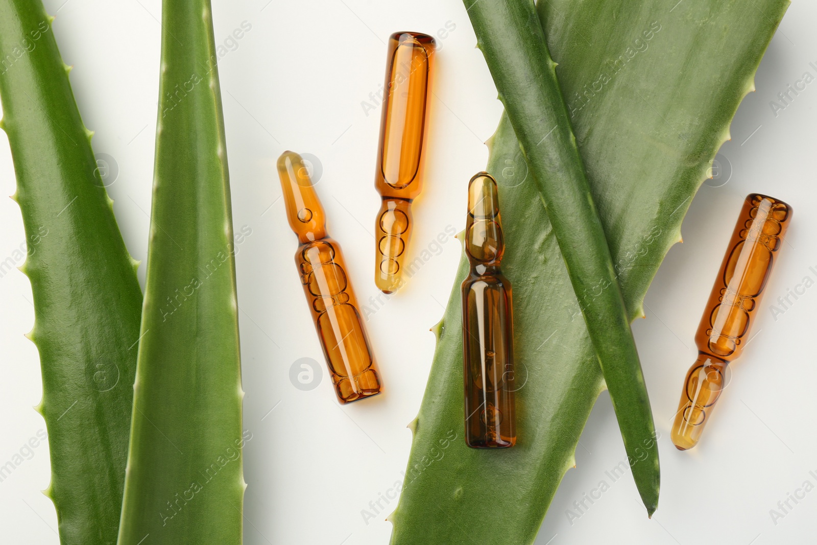 Photo of Skincare ampoules and aloe leaves on white background, flat lay