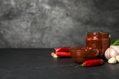 Photo of Tasty rhubarb sauce and ingredients on black table, space for text