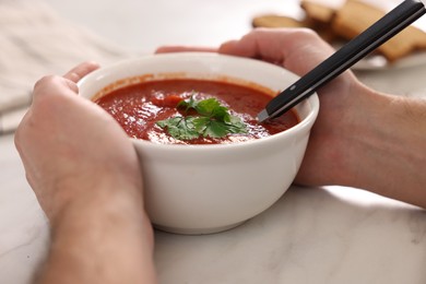 Photo of Man with delicious tomato soup at light table, closeup