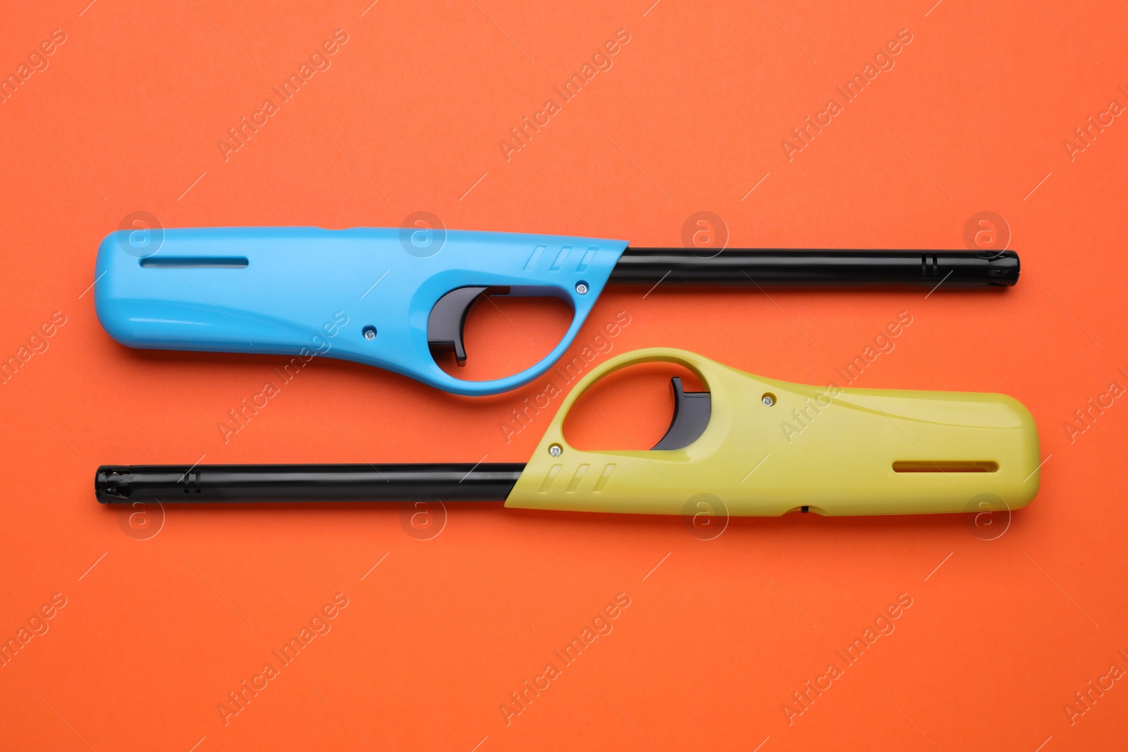 Photo of Gas lighters on orange background, flat lay