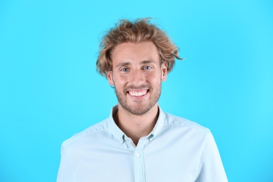 Handsome young man laughing on color background