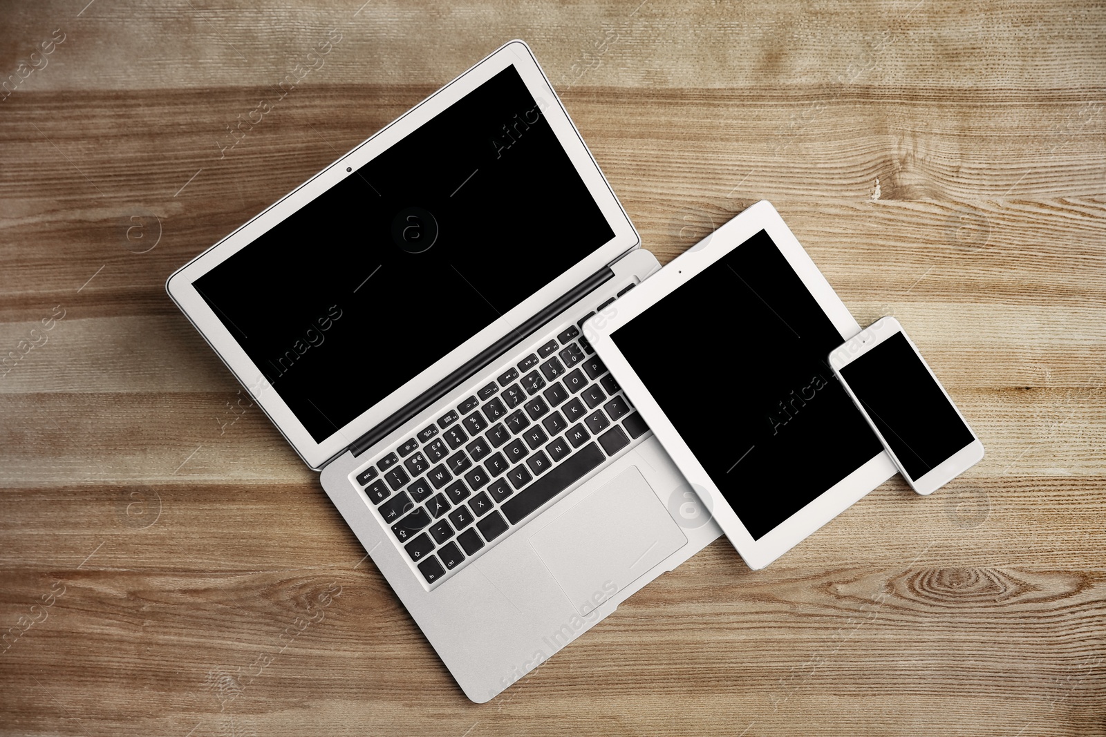 Photo of Devices with blank screens on wooden background, top view. Mock up for design