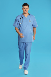 Handsome doctor in uniform walking on blue background