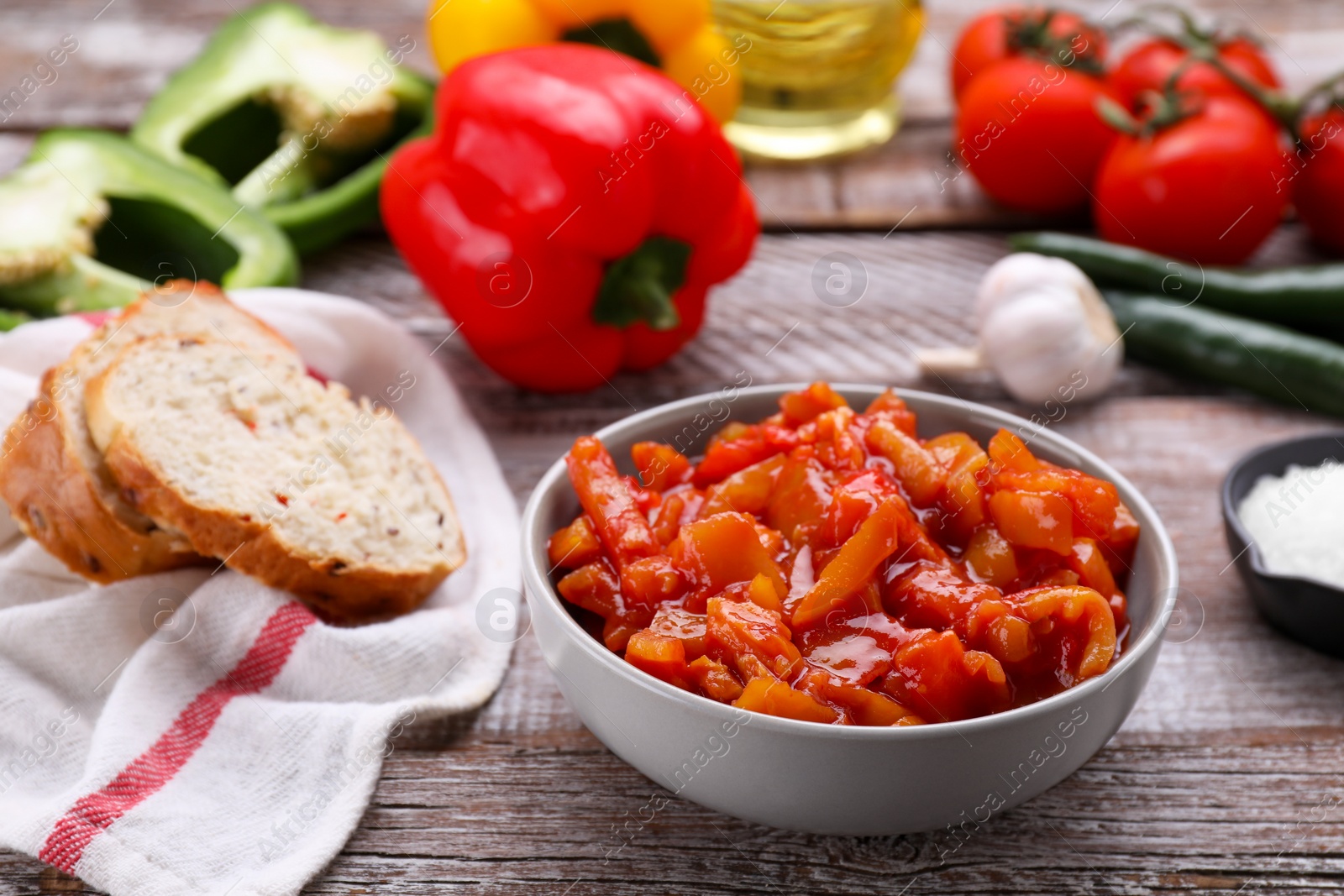 Photo of Bowl of delicious lecho and ingredients on wooden table