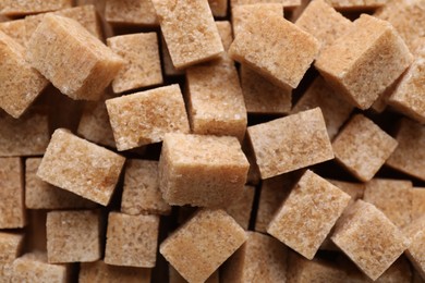 Photo of Different types of brown sugar as background, top view