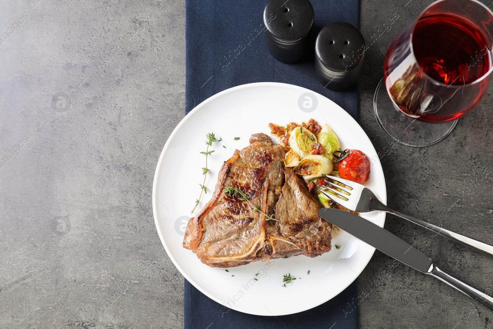 Photo of Delicious fried beef meat and vegetables served on grey table, top view. Space for text