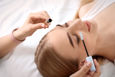 Photo of Beautician applying oil onto woman's eyelashes in salon