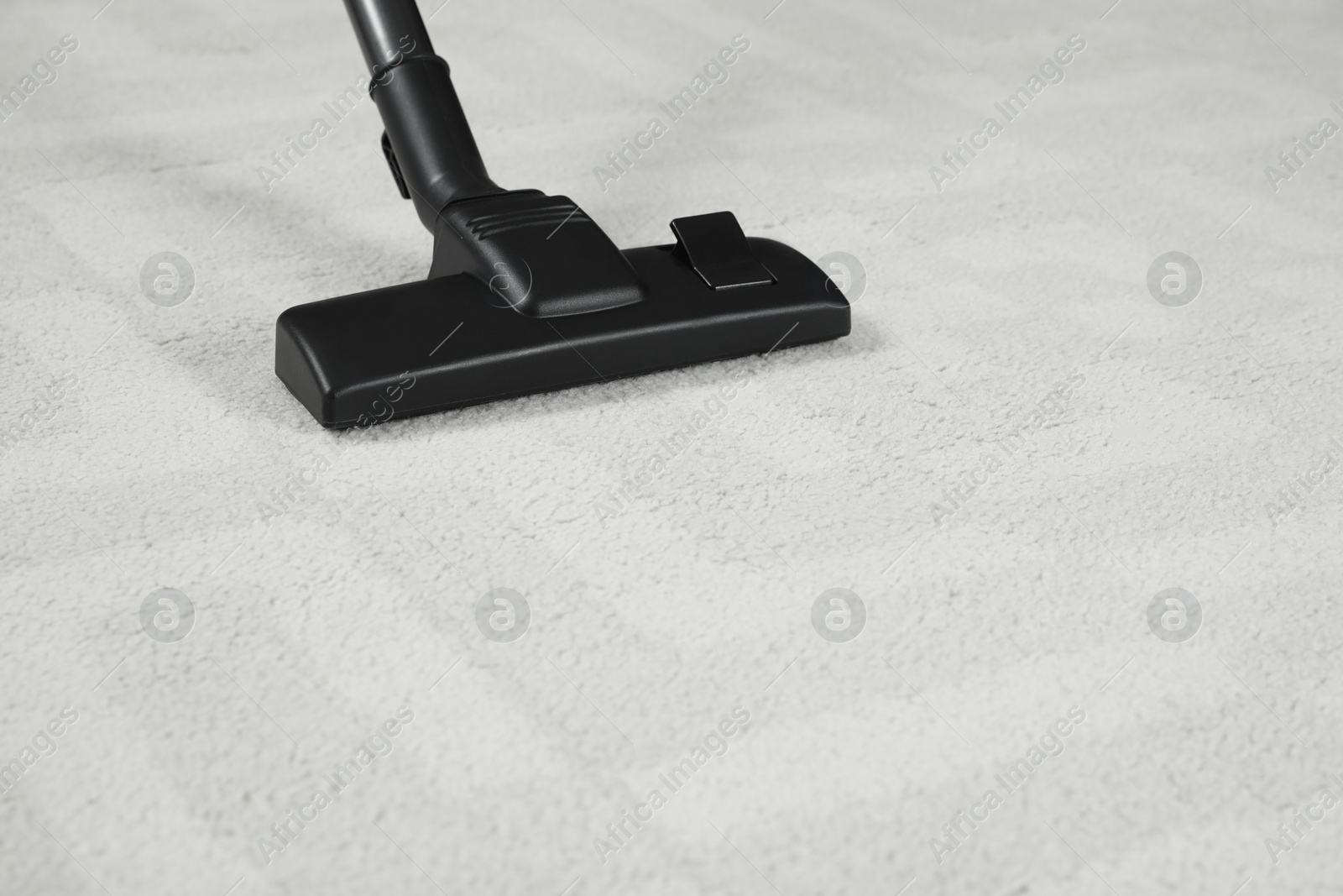 Photo of Removing dirt from white carpet with modern vacuum cleaner. Space for text