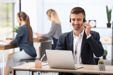 Photo of Male receptionist with headset at desk in office