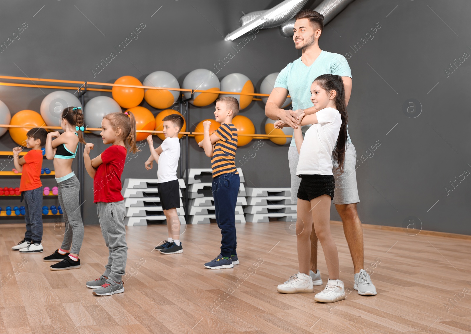 Photo of Cute little children and trainer doing physical exercise in school gym. Healthy lifestyle