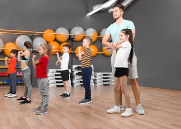 Cute little children and trainer doing physical exercise in school gym. Healthy lifestyle