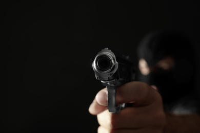 Professional killer on black background, focus on gun. Space for text