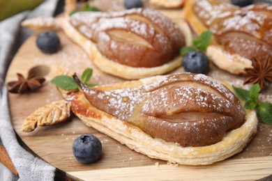 Delicious pears baked in puff pastry with powdered sugar served on table, closeup