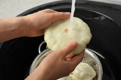 Photo of Woman washing pattypan squash above sink, closeup